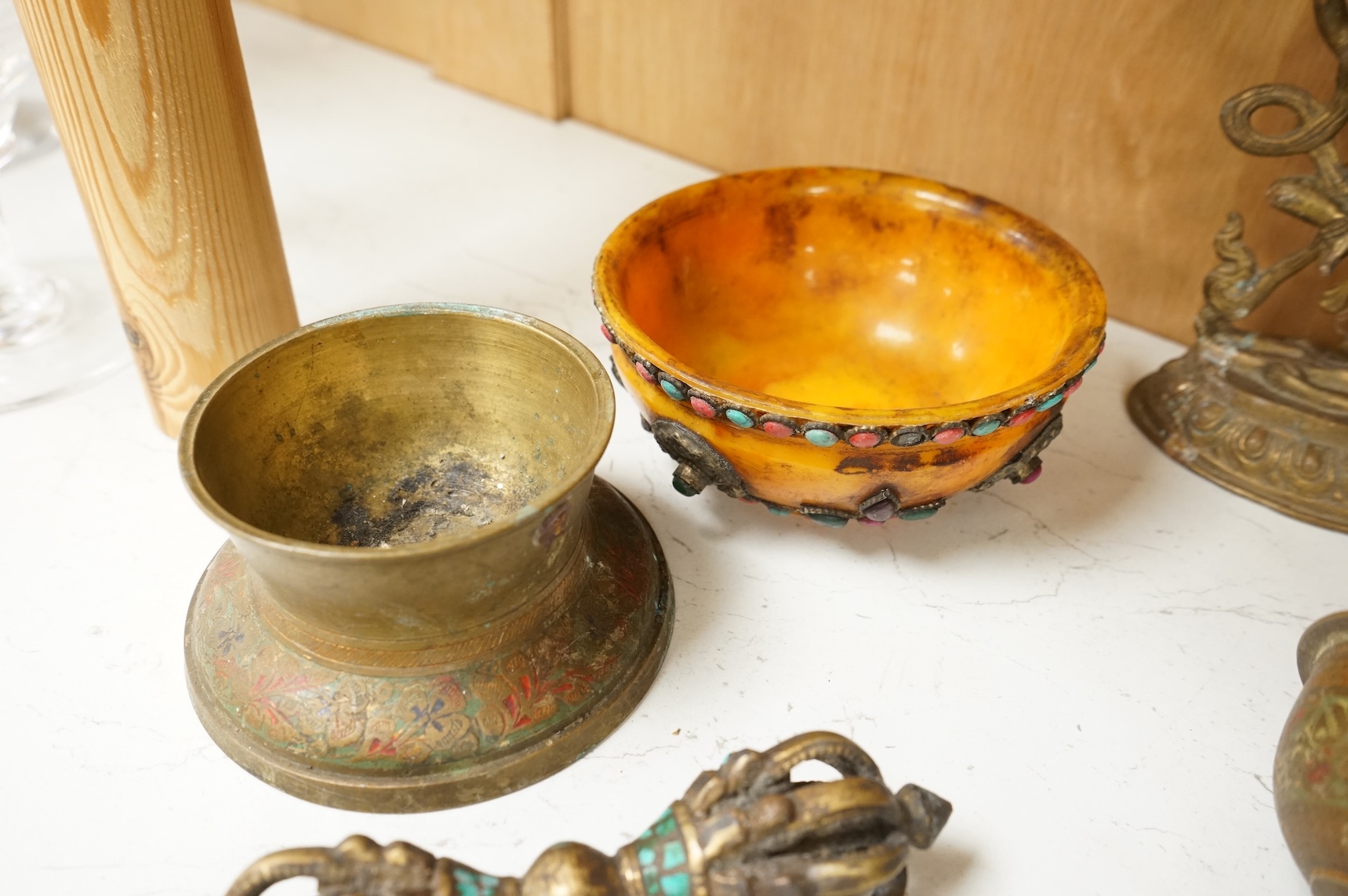 A group of Tibetan brass and mixed metal artefacts to include a brass vase with cabochon inset stones and figures of deities, largest 22cm high